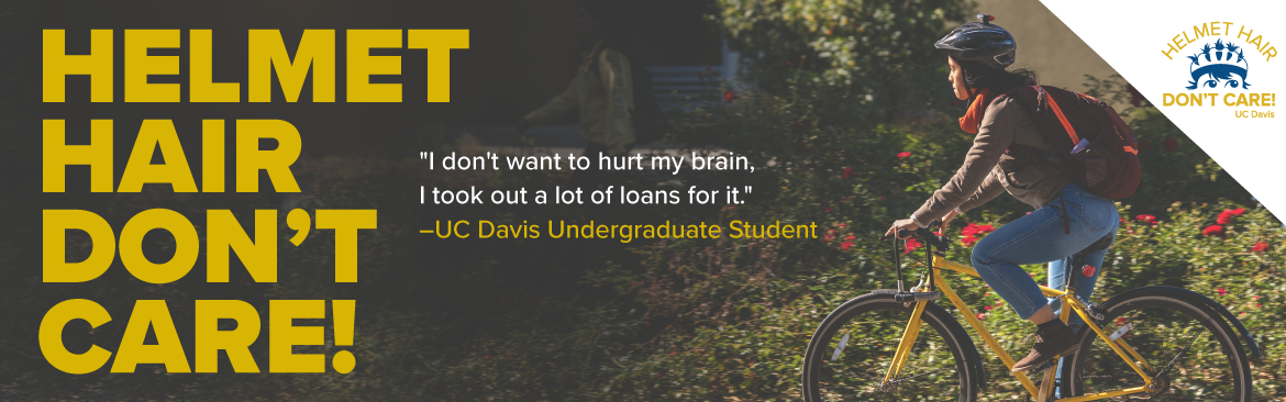 Student on bike at UC Davis wearing a helmet and cycling across campus.