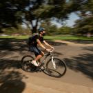 Student on bike at UC Davis wearing a helmet and cycling across campus.